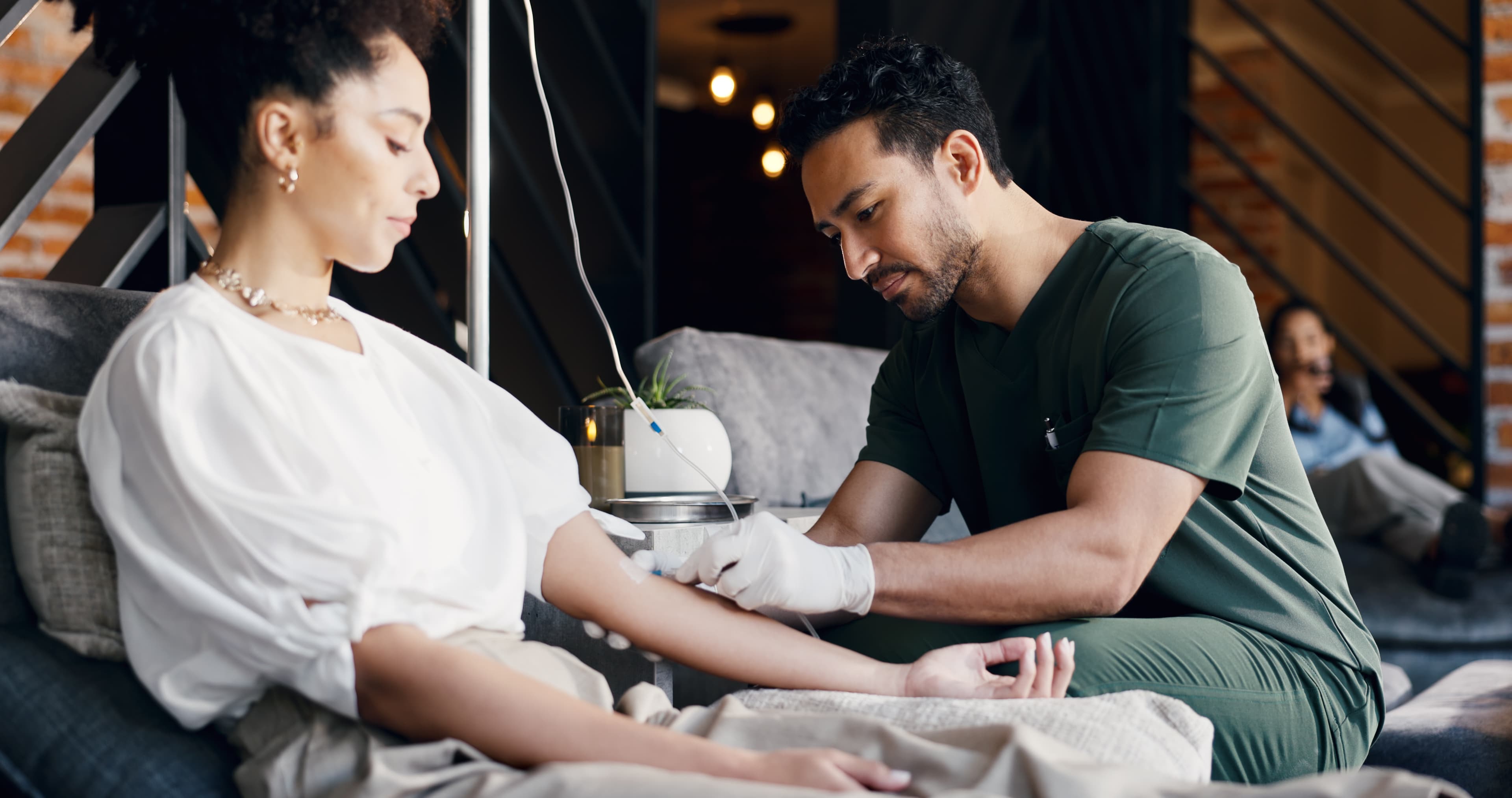 A guest relaxing in a lounge chair while one of Prime IV's Licensed Medical Professionals starts an IV drip