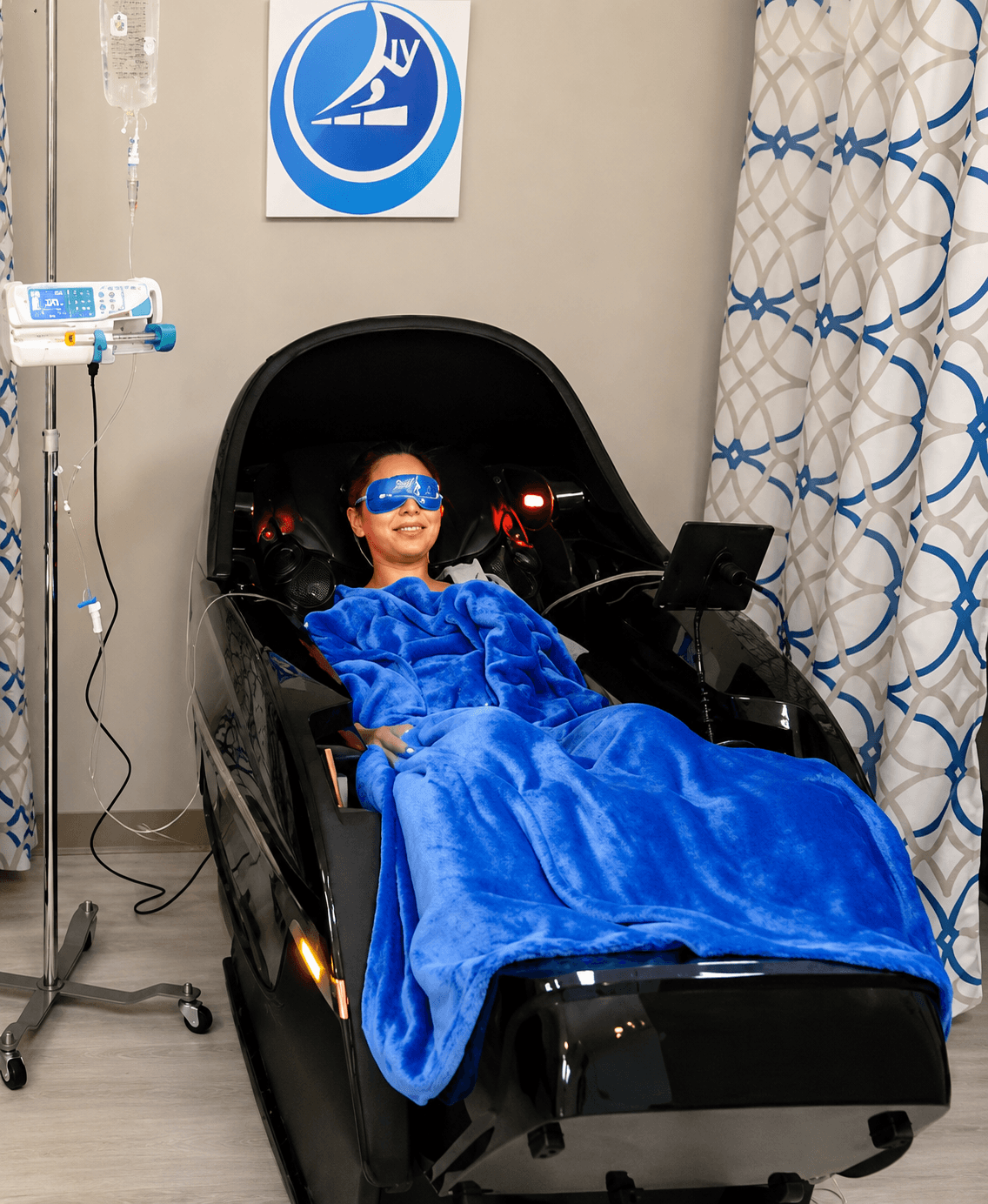 A relaxed client reclining in a heated massage chair with an LED eye mask and blanket during an IV therapy session at Prime IV Mesa